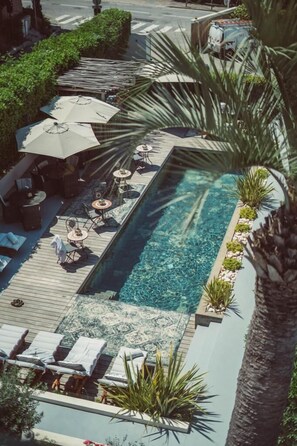 A rooftop pool area with lounge chairs, umbrellas, and a clear blue pool. - Hotel Le Mandala (Saint-Tropez)