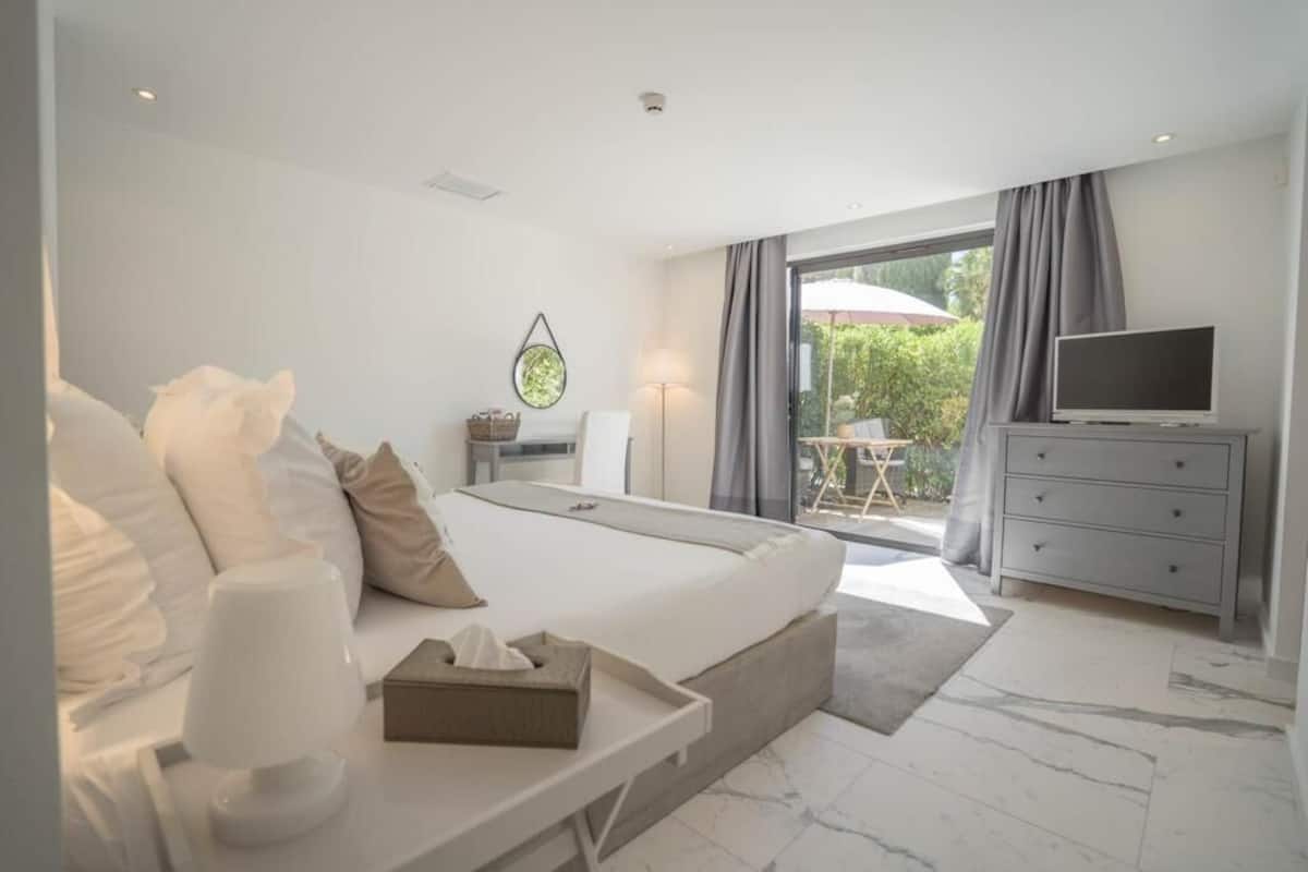 Una habitación de hotel moderna con una cama grande, televisión, escritorio y vistas al exterior.