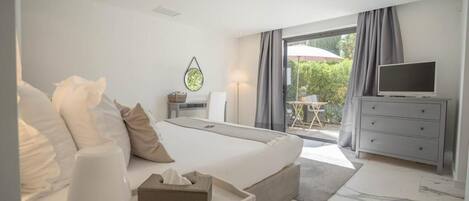 A modern hotel room with a large bed, a television, a desk, and a view of the outdoors.