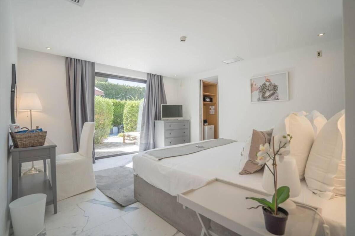 Un dormitorio moderno con una cama grande, televisor, escritorio y vistas al exterior.