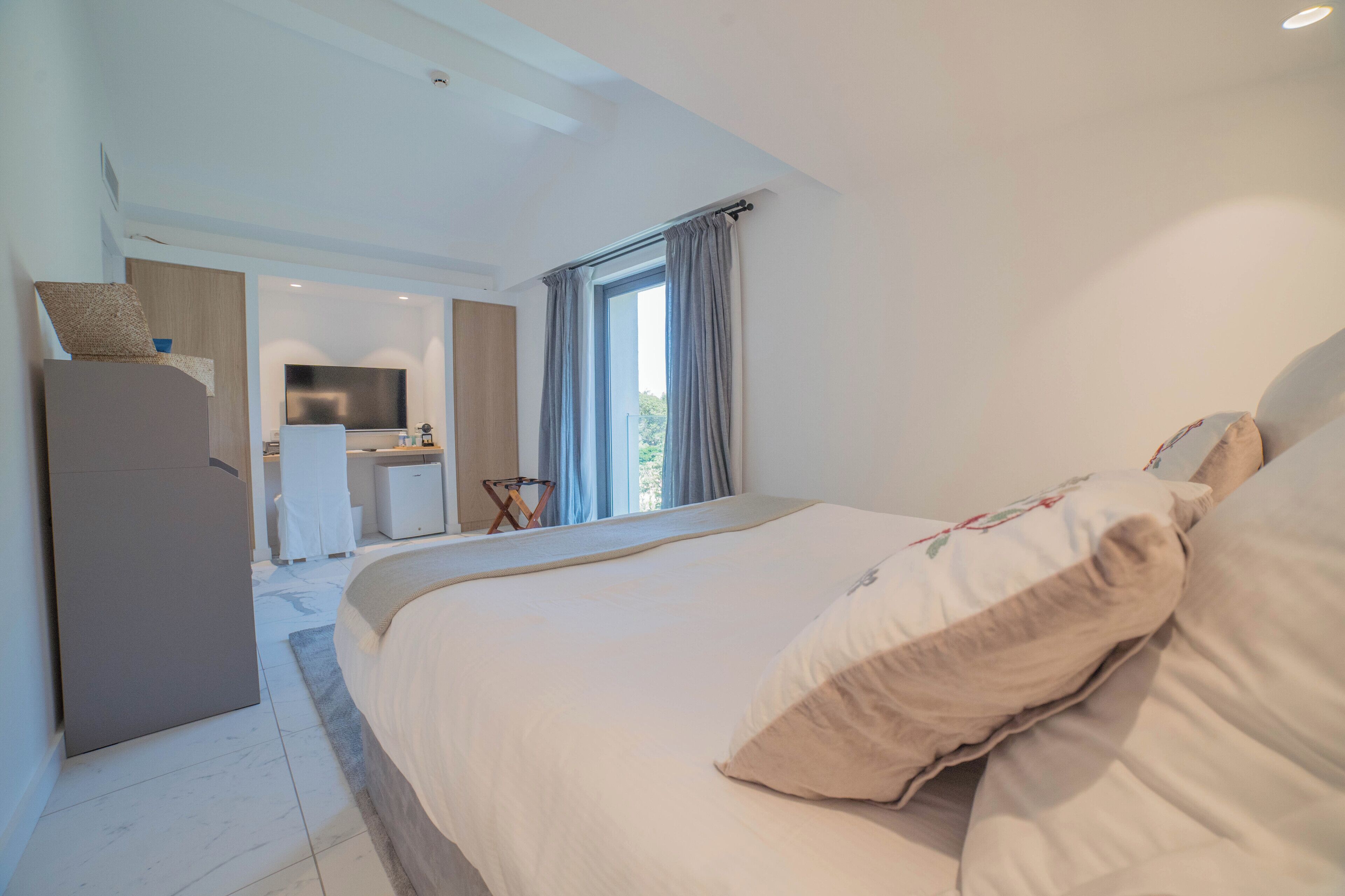 A modern hotel room with a large bed, a desk, and a bathroom.
