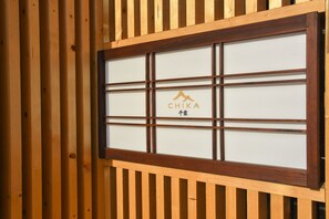 Una ventana con marco de madera y diseño de cuadrícula, con el logotipo "CHIKA" en el centro.