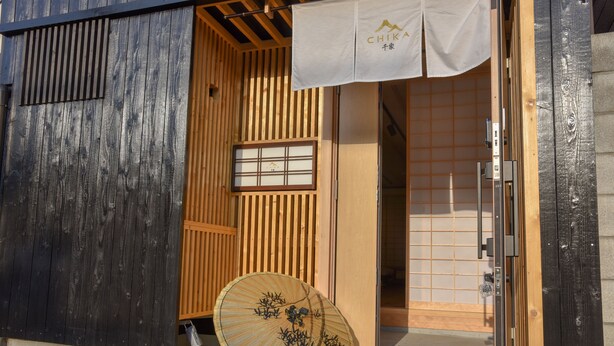 A traditional Japanese building with a wooden exterior, a sliding door, and a decorative fan outside. - Chika Seiryu (Kyoto)