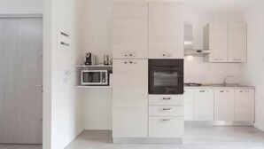 Een moderne keuken met witte kastjes, een ingebouwde magnetron, een fornuis en een spoelbak.