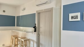 Een moderne keuken met een wit aanrecht, houten krukken, een witte deur en een luchtverfrisser aan de muur.