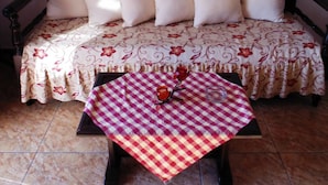 Une pièce chaleureuse avec un canapé-lit, une nappe à carreaux et un tableau représentant un bateau accroché au mur.