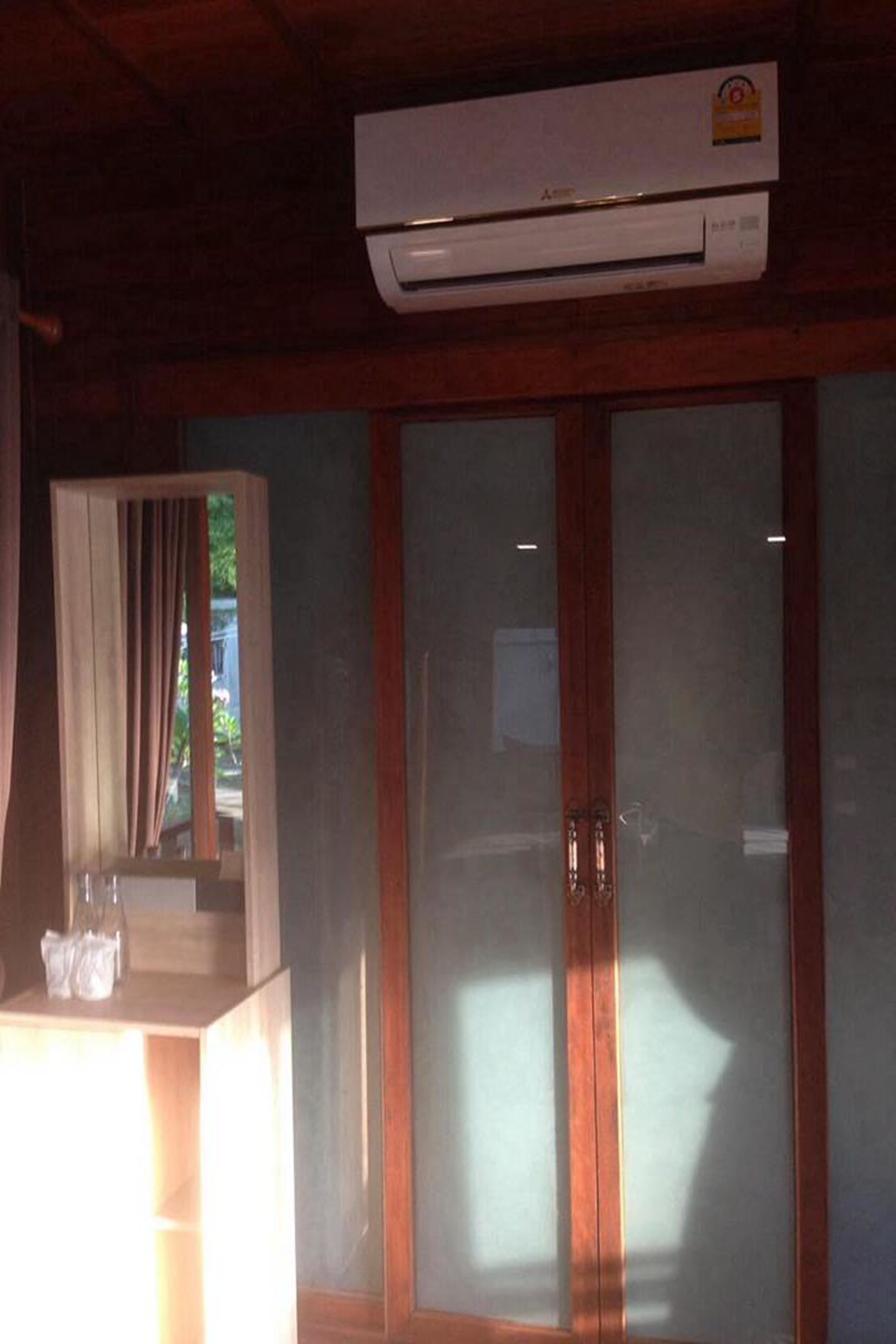 A room with a wooden ceiling, a glass door with a wooden frame, and an air conditioning unit mounted above the door.