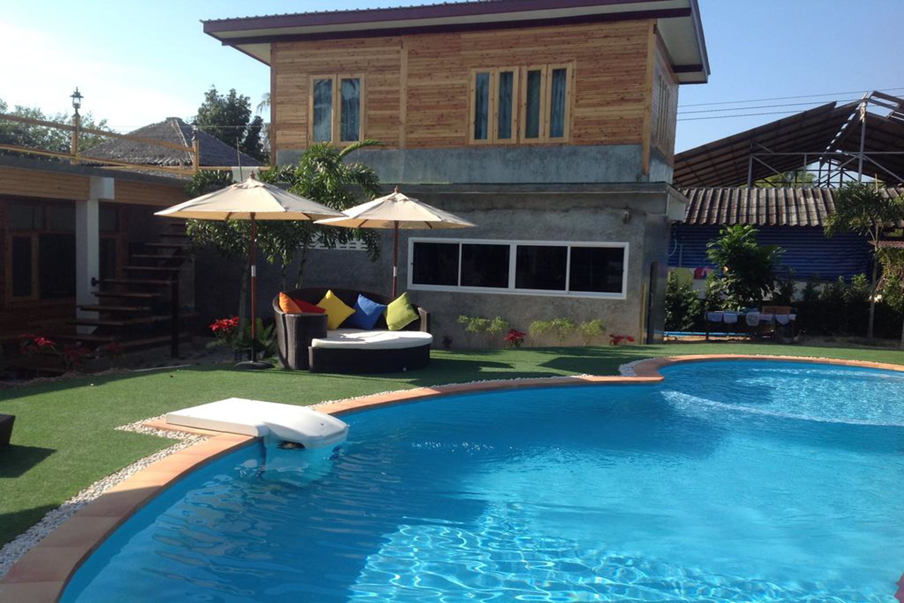 A swimming pool with a wooden house in the background.