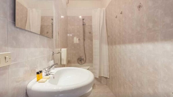 Une salle de bain avec un grand lavabo, une douche et un miroir.