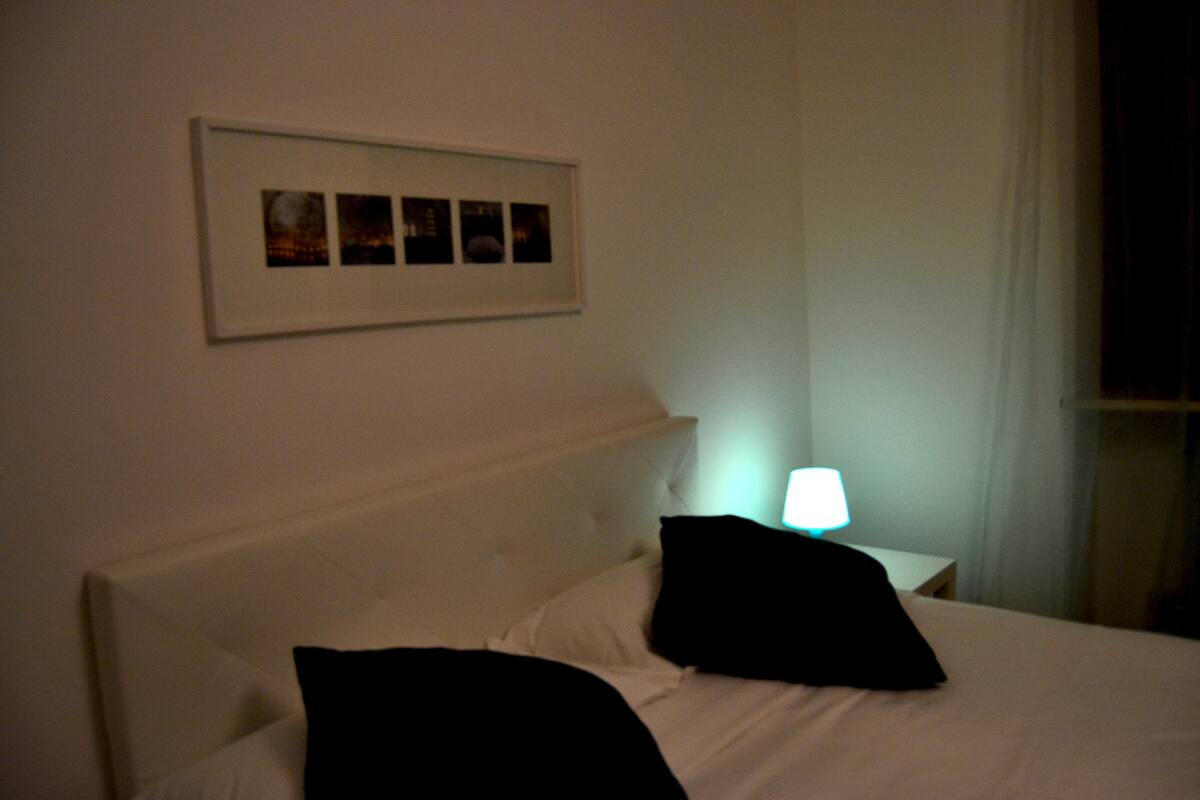 Une chambre d’hôtel avec un lit, une table de chevet avec une lampe et un tableau encadré au mur.