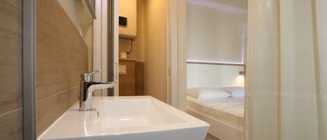 A modern bathroom with a white sink and a shower area.