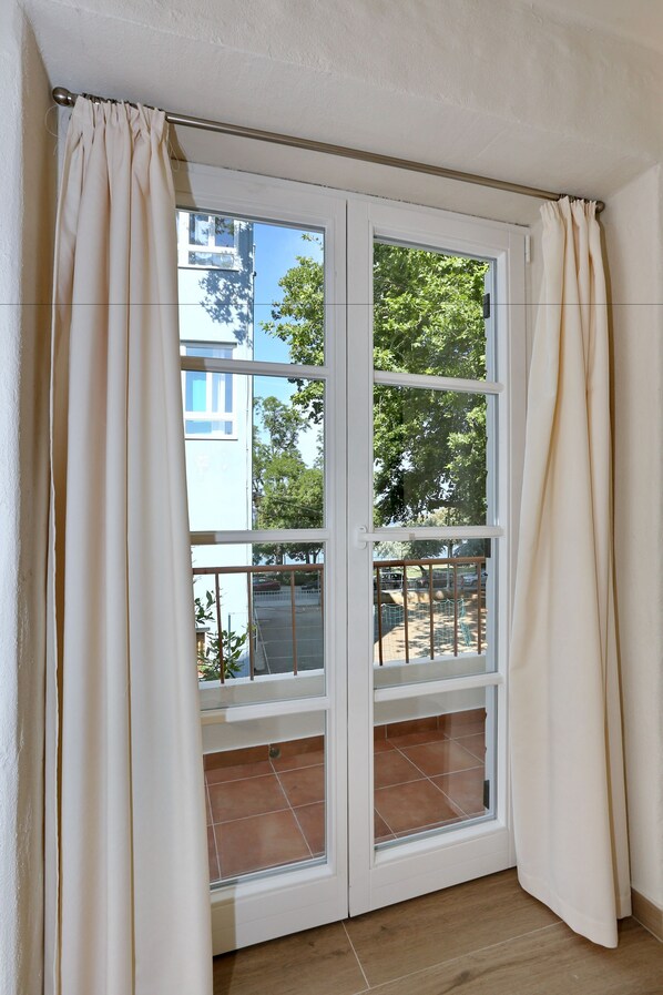 A room with a sliding glass door leading to an outdoor area with a tiled floor and a view of trees and a building. - Idassa Palace (Zadar)