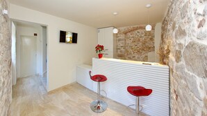 Een moderne badkamer met een stenen wand, een wit wastafelmeubel en twee rode barstoelen.