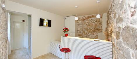 A modern bathroom with a stone wall, a white sink vanity, and two red bar stools.
