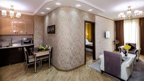 A modern hotel room with a kitchen area, a dining table, and a living area with a sofa and armchairs. - Dat Exx Apartments (Tbilisi)