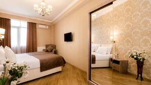 A hotel room with a large bed, a bedside table, a mirror, and a potted plant. - Dat Exx Apartments (Tbilisi)