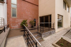 A building exterior with a brick facade, a concrete staircase, and a metal handrail.