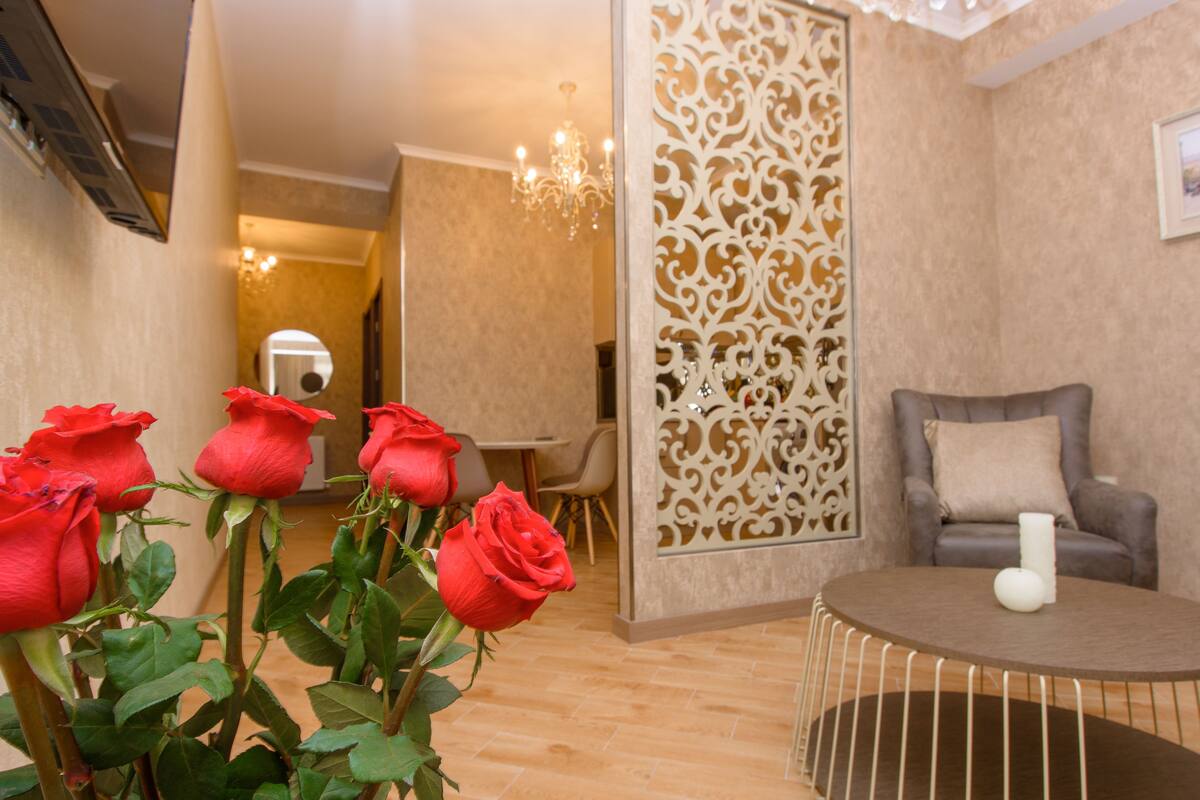 A room with a round table, a sofa, and a decorative partition.