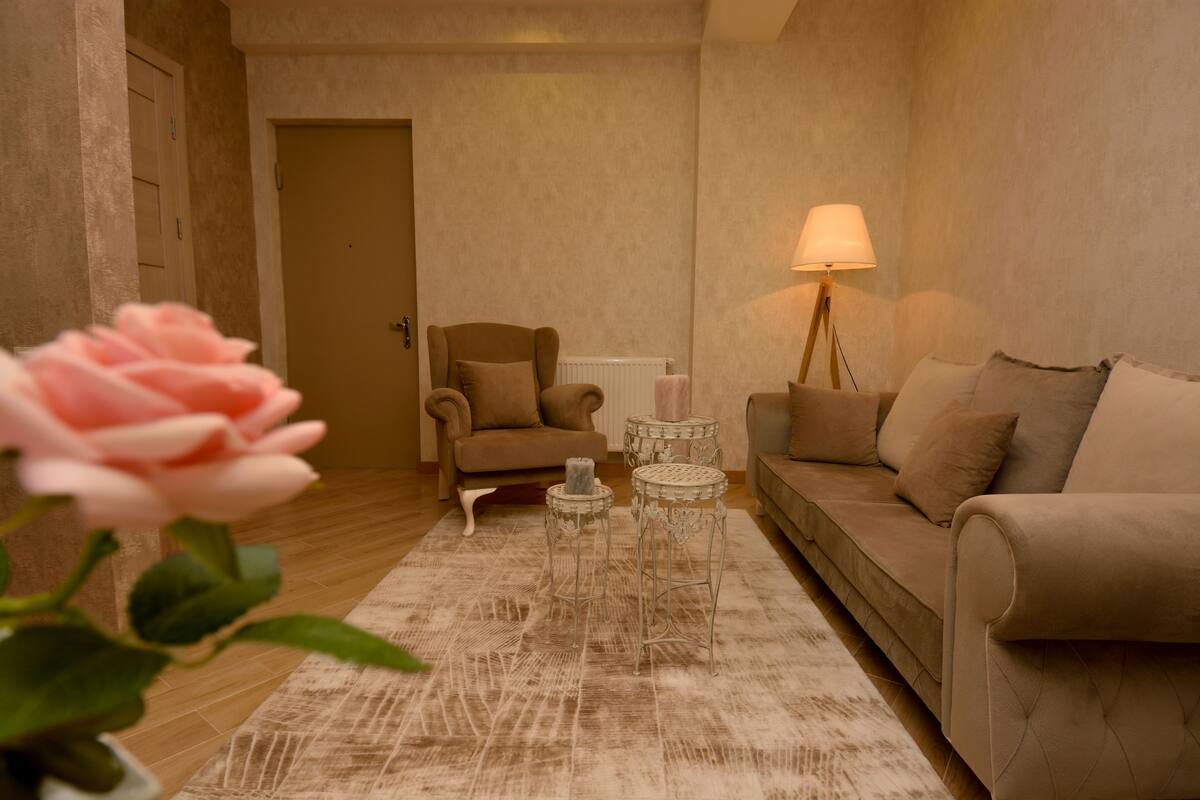 A living room with a beige sofa, a small armchair, a round coffee table, and a floor lamp.