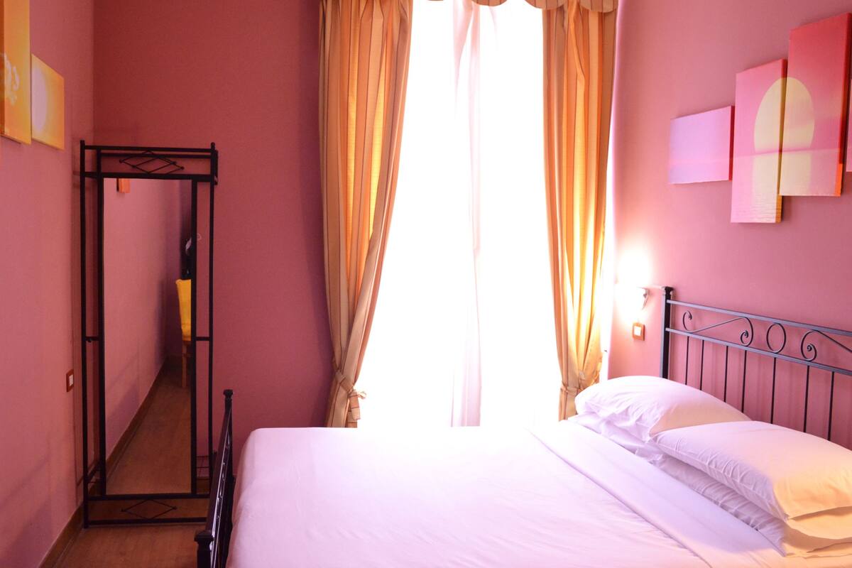 Ein Schlafzimmer mit einem Bett, einem Kleiderschrank und einem Fenster mit Vorhängen.