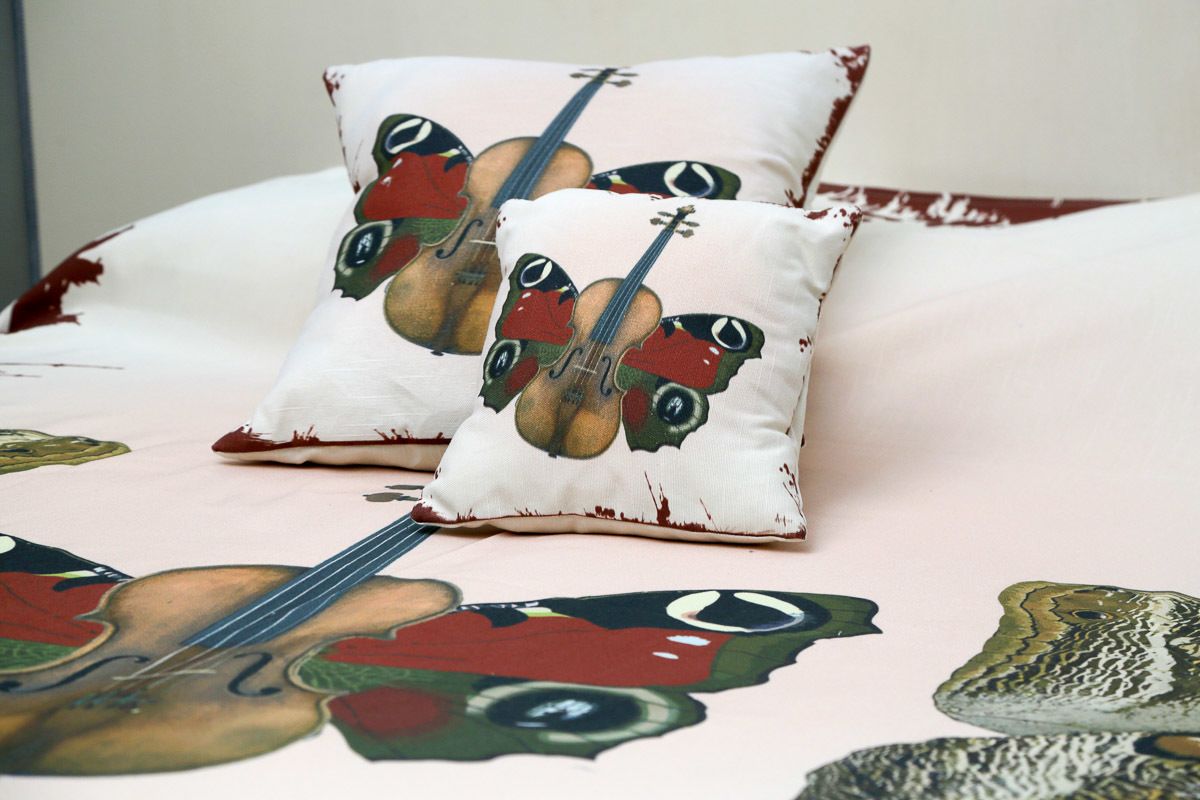 A bed with a floral patterned bedspread and two pillows with violin designs.