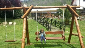 Un columpio de madera con un banco en un área con césped.