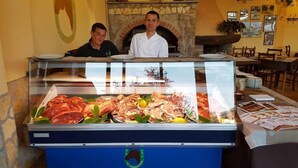 Mostrador de carnes con diversos cortes y un chef al fondo.