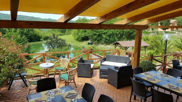 Un patio exterior con mobiliario de mimbre, una mesa lista para comer y vistas de un paisaje exuberante.