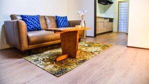 Ein Wohnzimmer mit einem braunen Ledersofa, einem Holztisch und einem gemusterten Teppich.