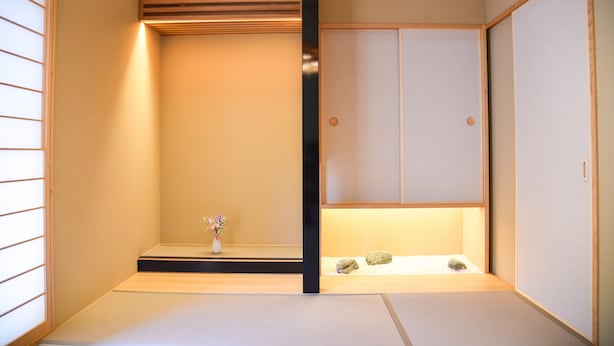 Ein traditioneller japanischer Raum mit Tatami-Bodenbelag, Shoji-Schirm und einem kleinen Steingarten.