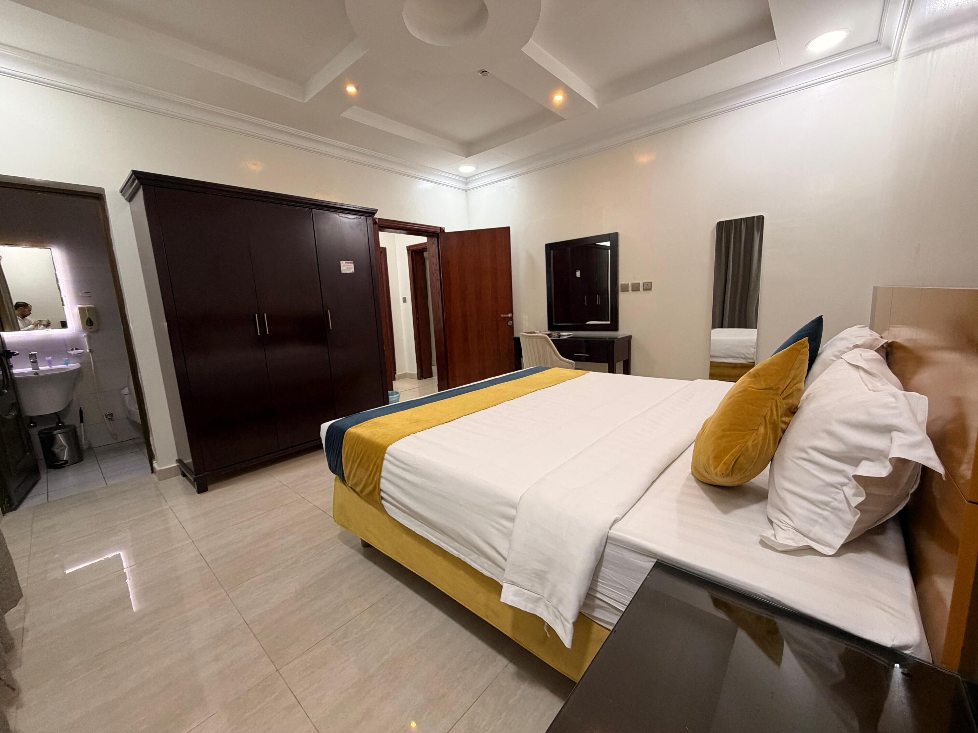 A hotel room with a bed, a desk, a TV, a wardrobe, and a bathroom.