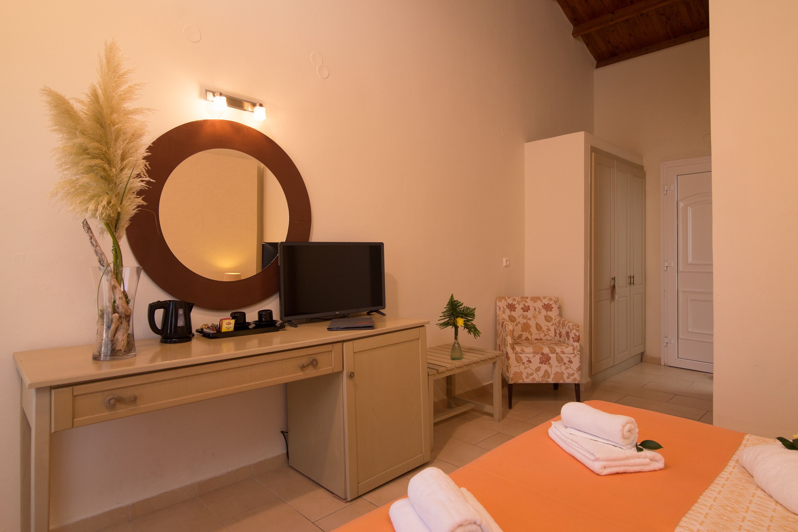 A bedroom with a bed, a TV, a desk, a chair, and a mirror.