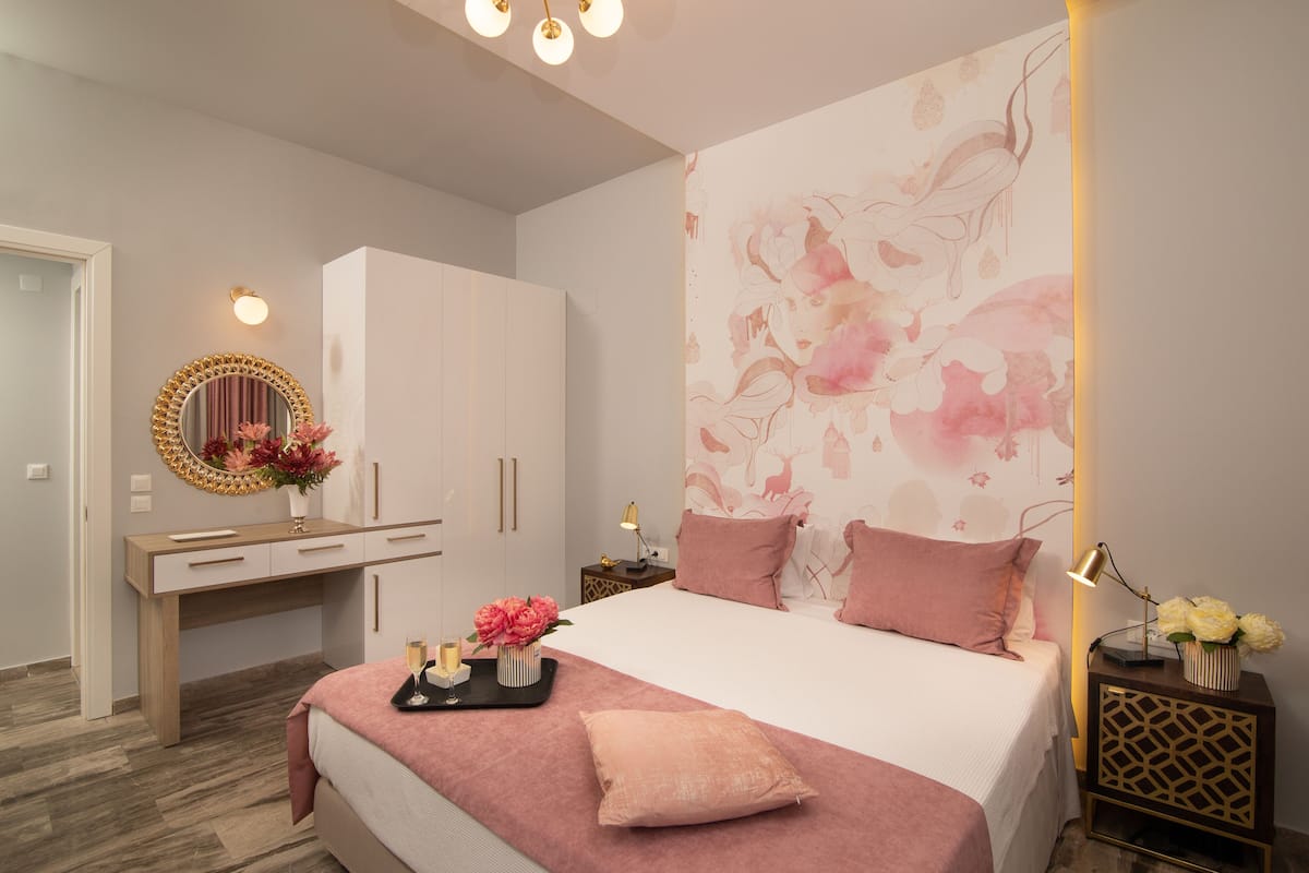 A bedroom with a bed, bedside table, dresser, and a wall with floral wallpaper.