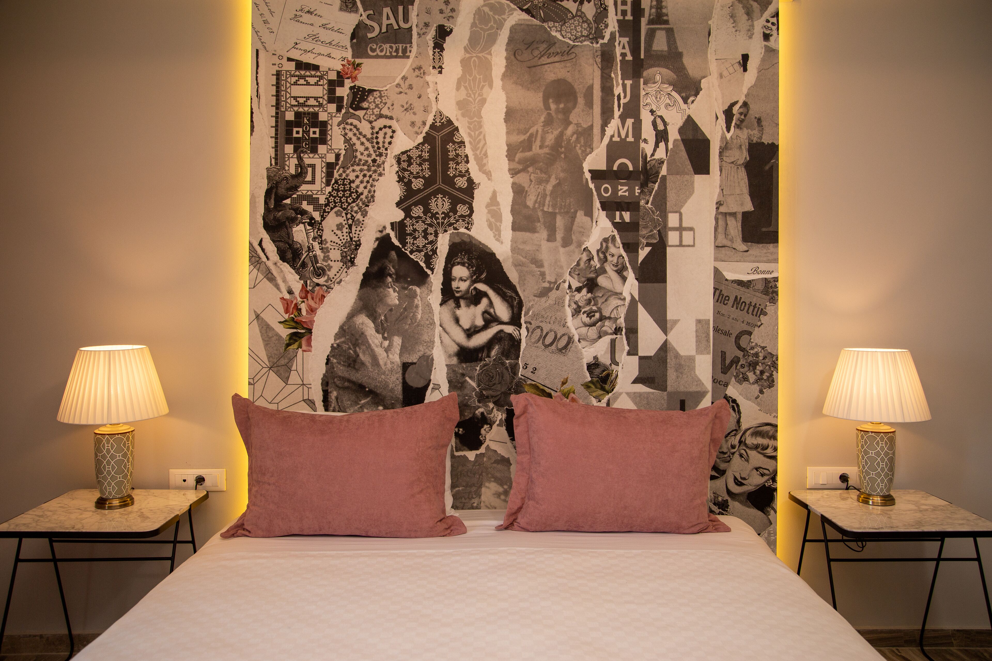 Quarto com uma cama, duas mesas de cabeceira com luminárias e uma tapeçaria na parede.