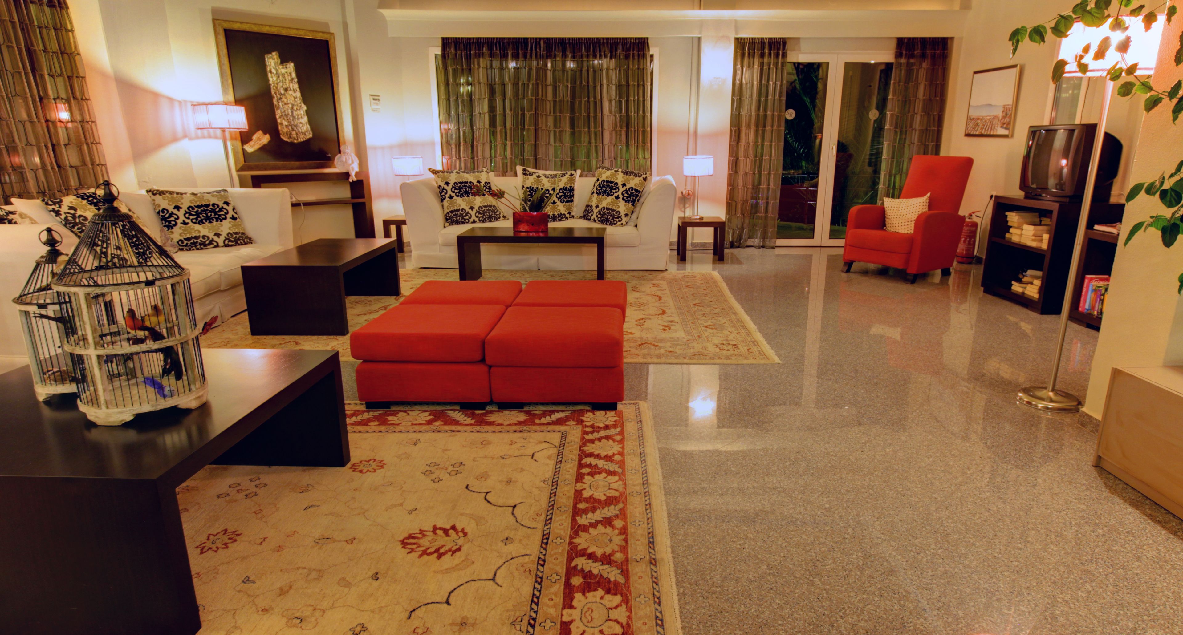 A living room with a sofa, red ottoman, coffee table, and a television.