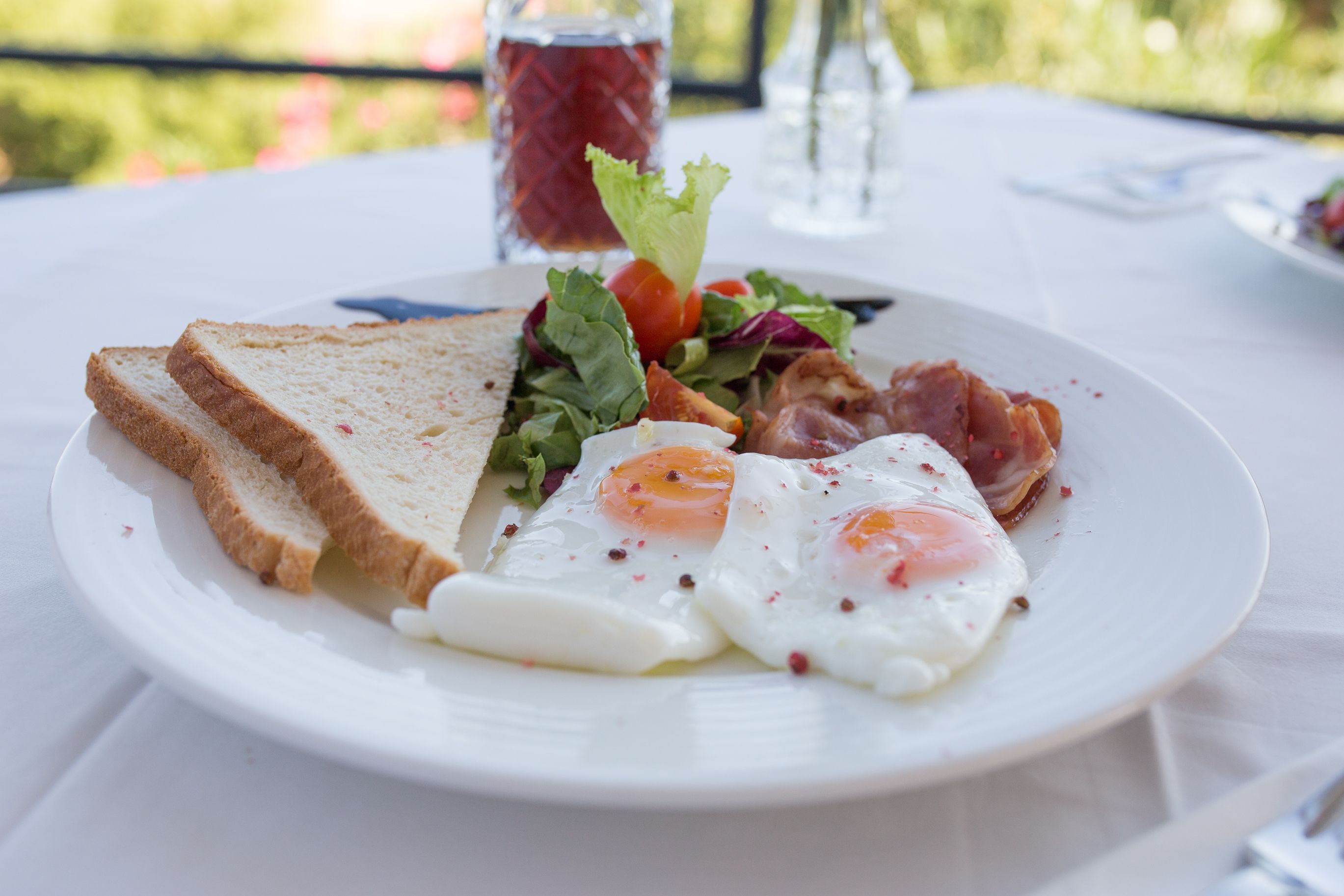 Ein Teller mit Toast, Eiern und Salat auf einer weißen Tischdecke.