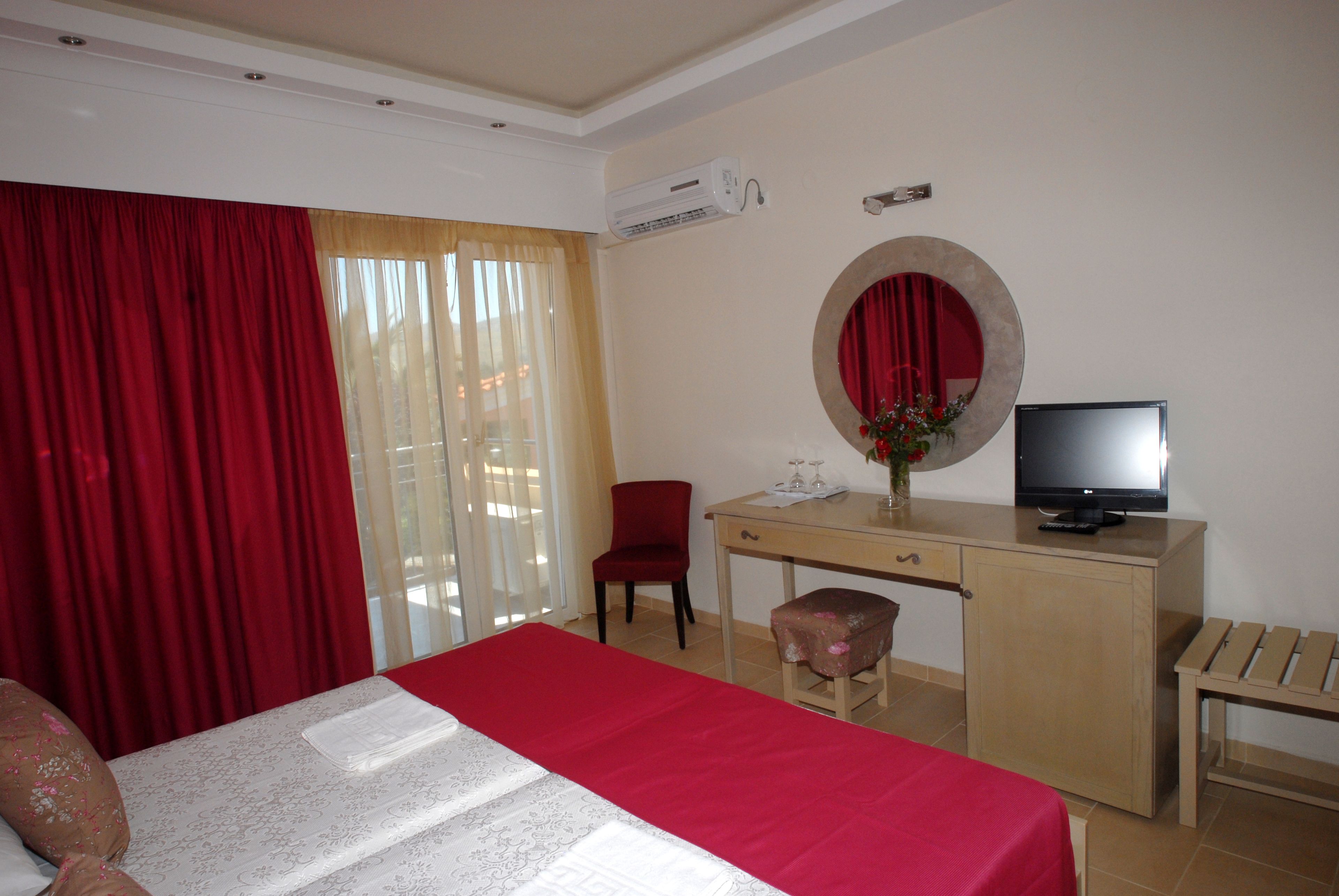 A hotel room with a bed, a desk, a television, a chair, and a small table.