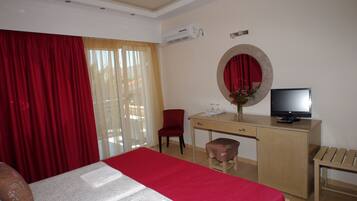 Habitación de hotel con cama, escritorio, televisor, silla y una mesita.
