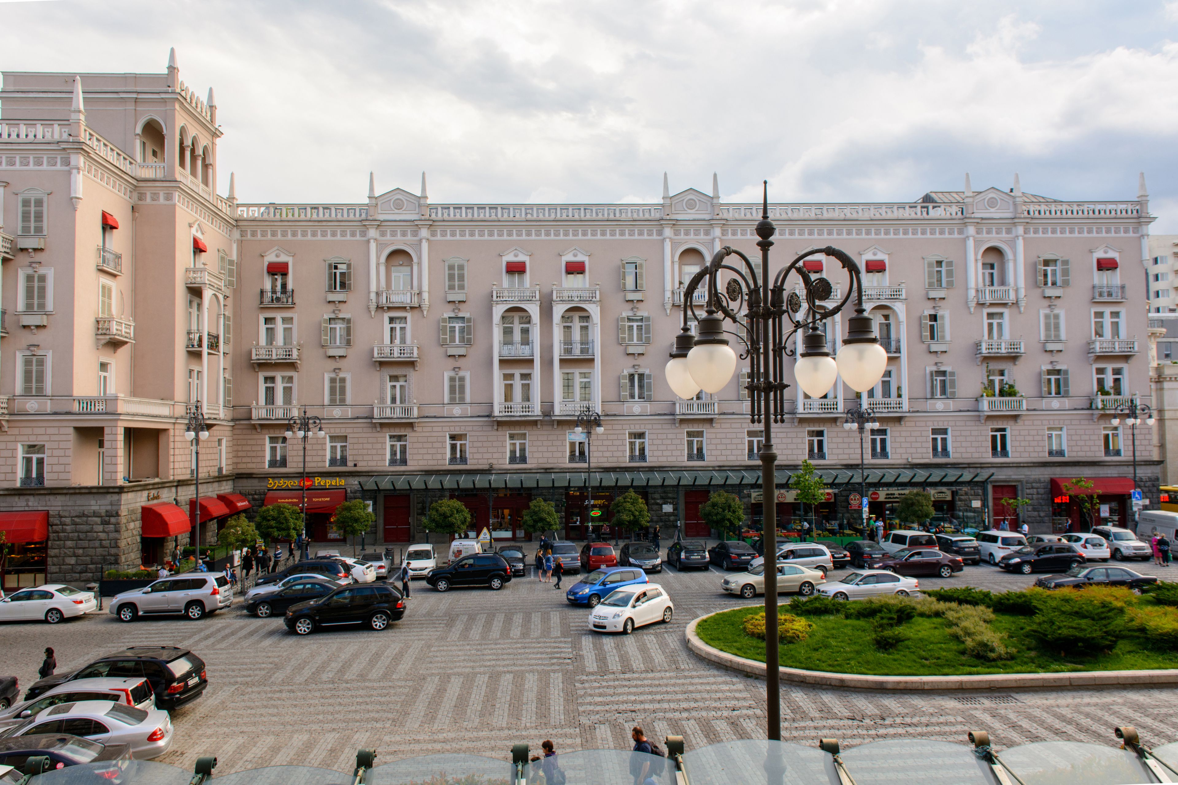 Un hotel grande con varios pisos, un patio central y un estacionamiento lleno de coches.