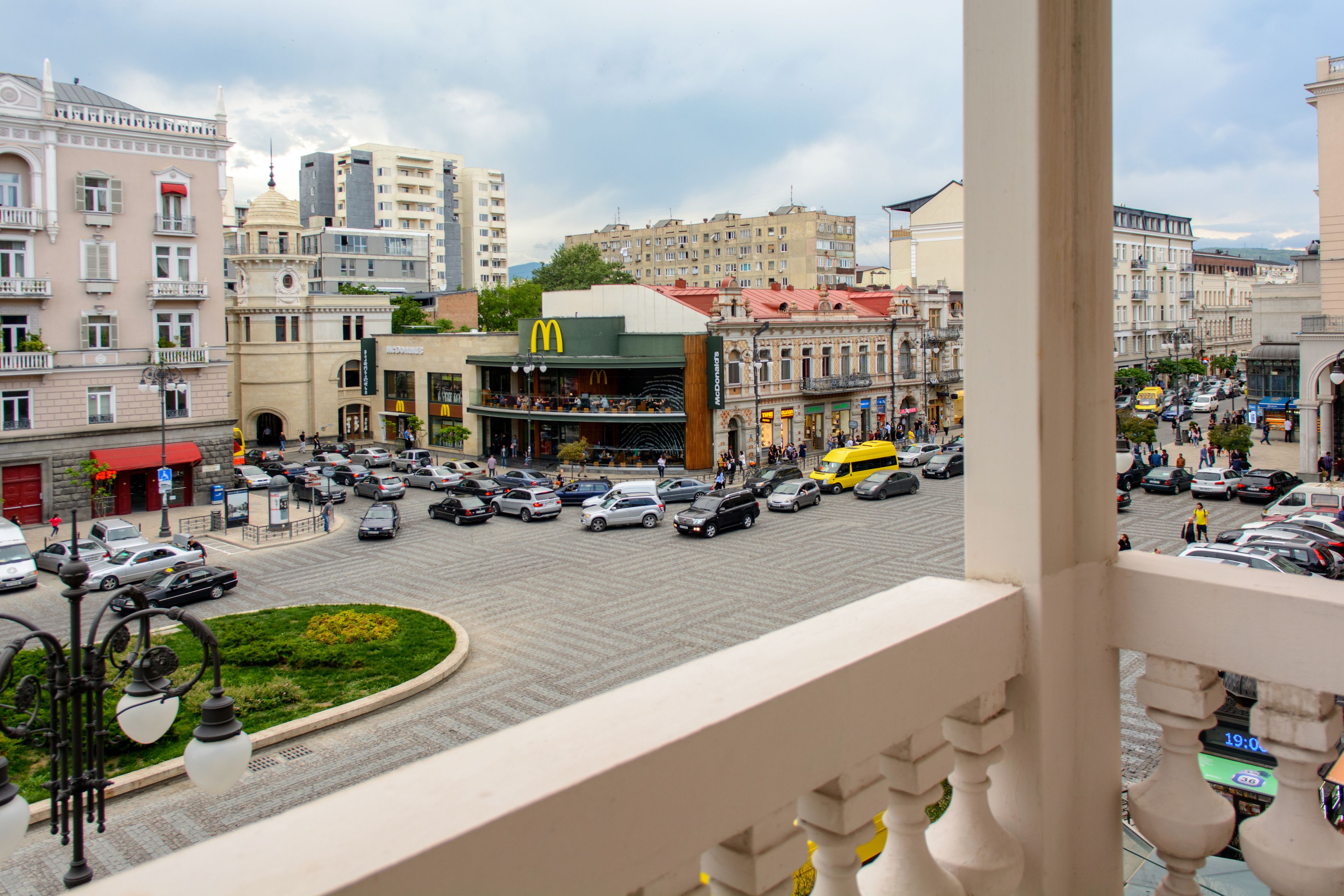 Une rue animée en plein centre-ville, avec un restaurant McDonald's, des bâtiments historiques et un rond-point.