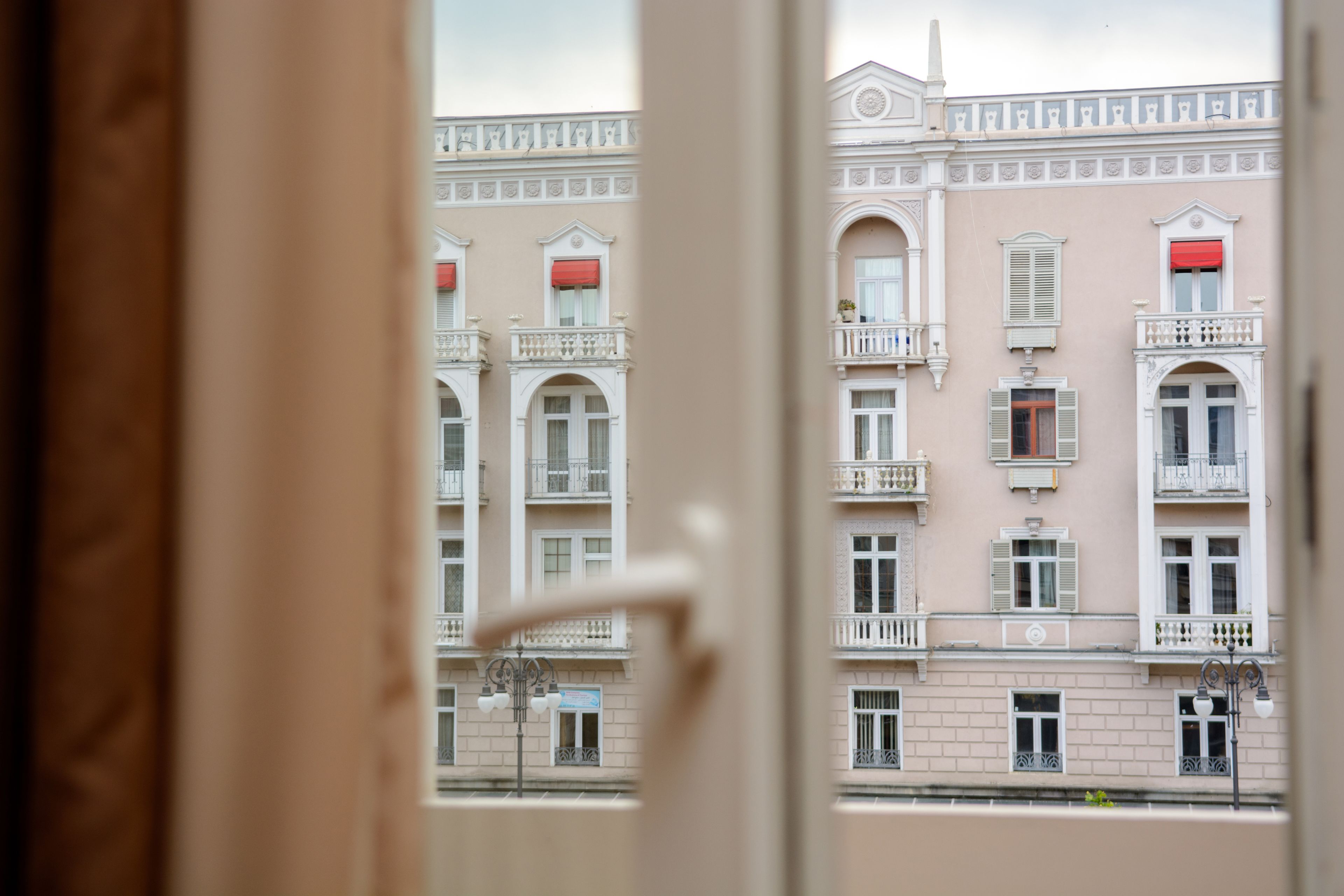 Un edificio con varios balcones y ventanas, visto a través de un portal abierto.