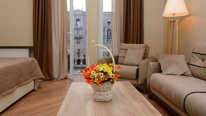 Una habitación de hotel con una cama, un sofá, una mesa con un florero y una lámpara.
