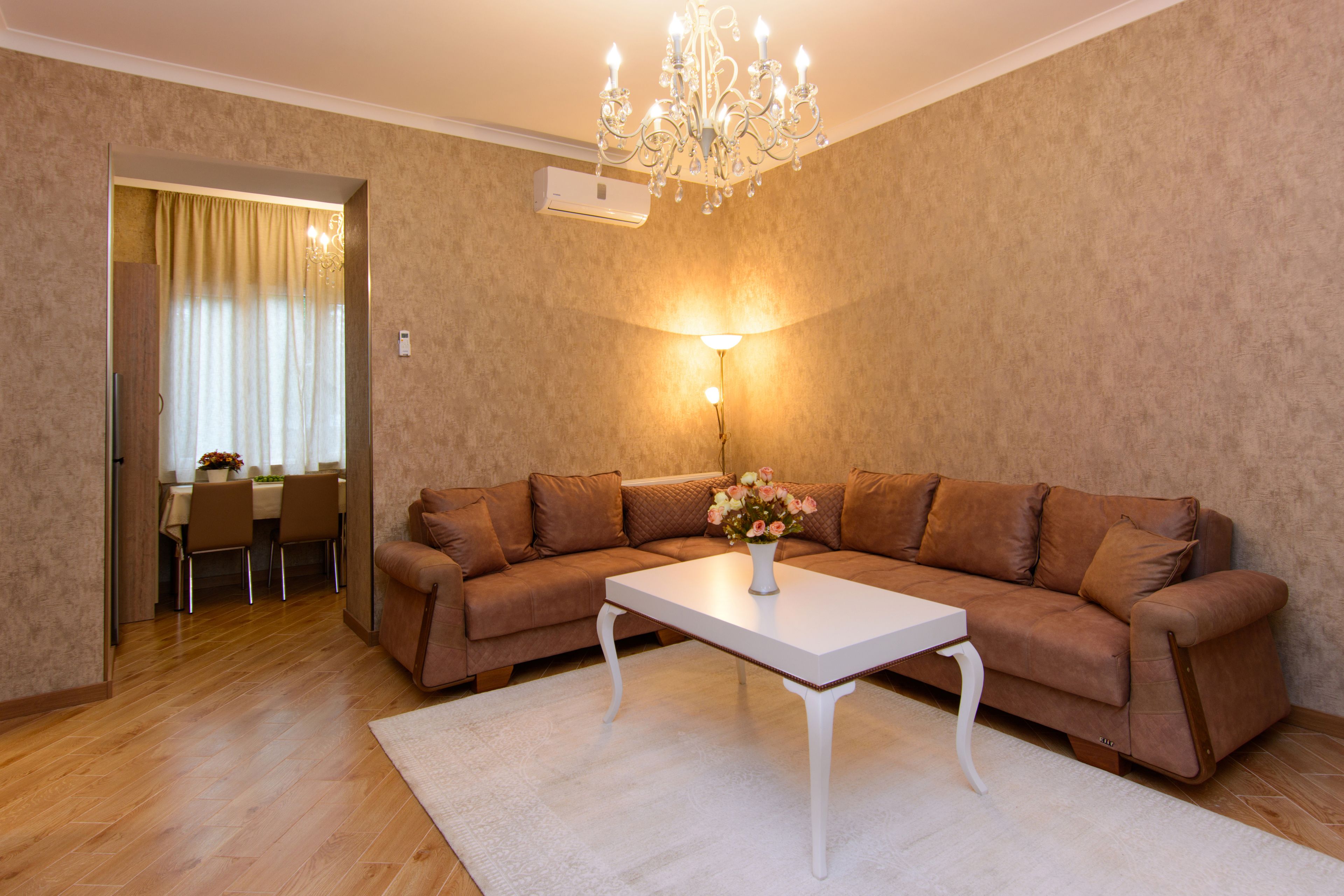A living room with a brown sofa, a white coffee table, and a chandelier.