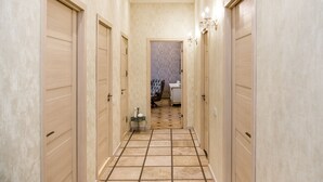 Un pasillo con puertas de madera, piso de baldosas y un candelabro.