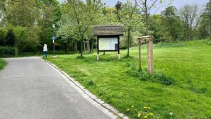 A paved path with a signpost and a map in a park setting. - Pension Alscher (Goslar)