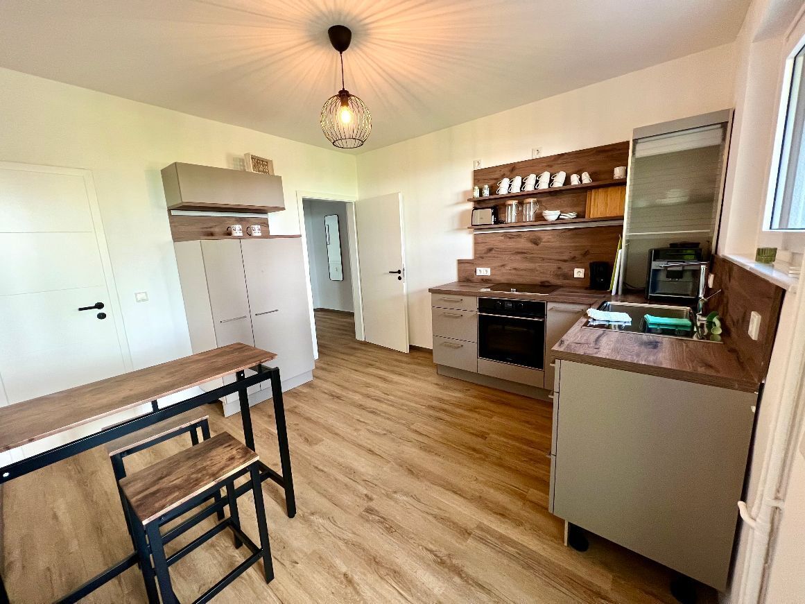 A modern kitchen with wooden flooring, built-in appliances, and a dining area with a bench.