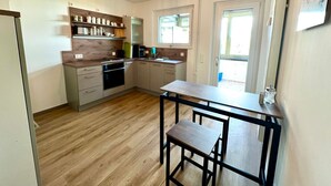 A modern kitchen with wooden flooring, a built-in oven, and a dining area with a table and bench. - Pension Alscher (Goslar)