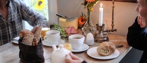 A breakfast setting with a table, plates, cups, a teapot, and a candle.