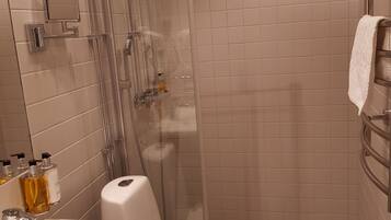 Ein Badezimmer mit einer gläsernen Duschkabine, einem weißen Waschbecken und einer Toilette.