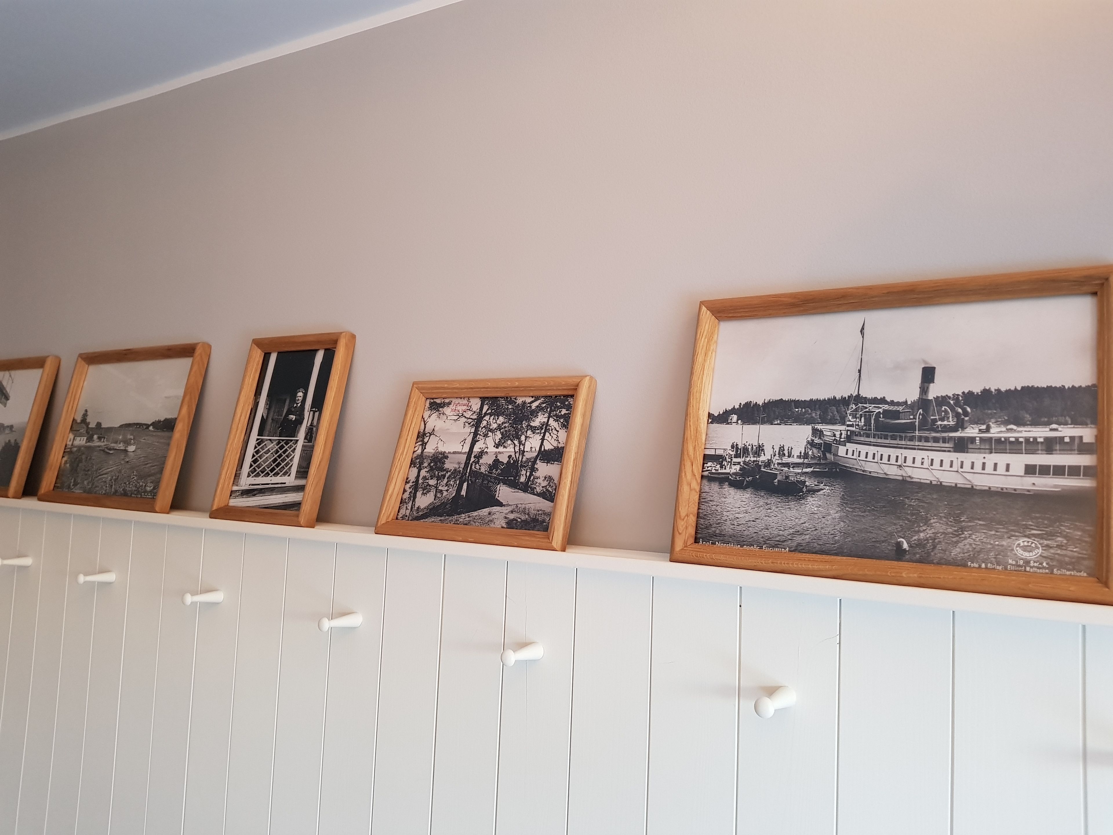A wall with a row of framed black and white photographs.